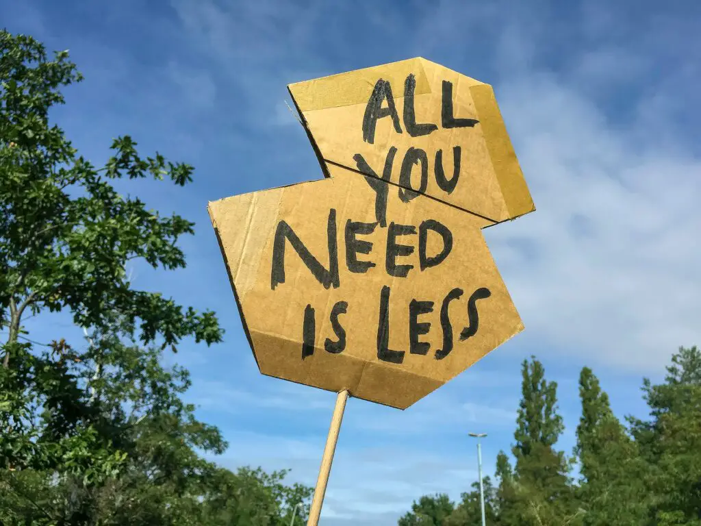 a cardboard sign that says all you need is less